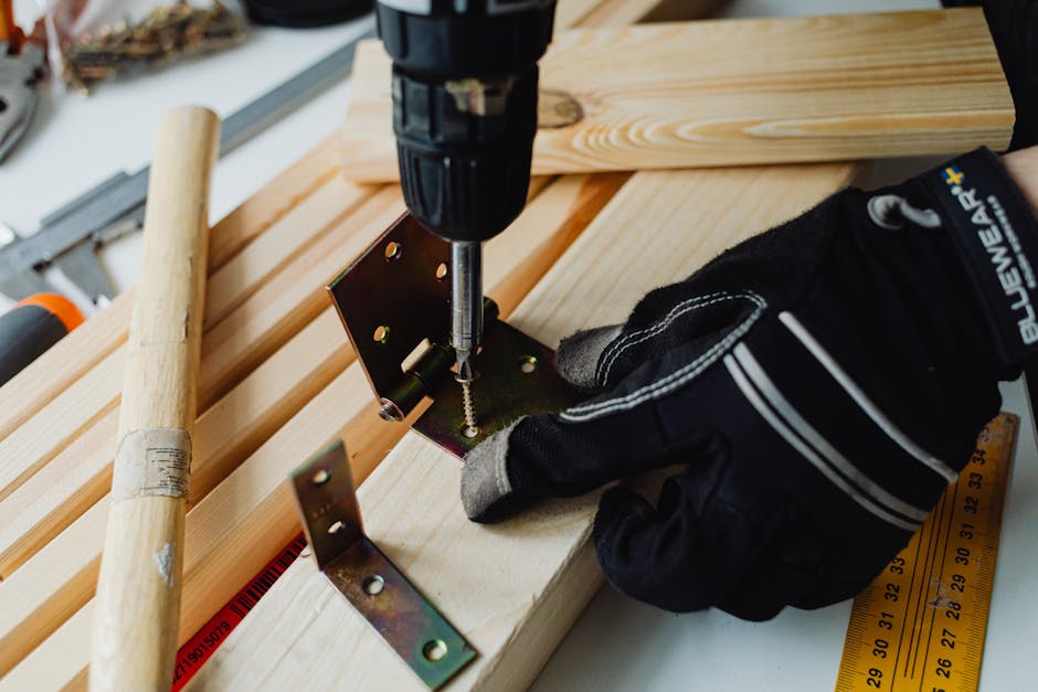 Detailed view of a woodworking project with a power drill, bracket, and safety gloves.