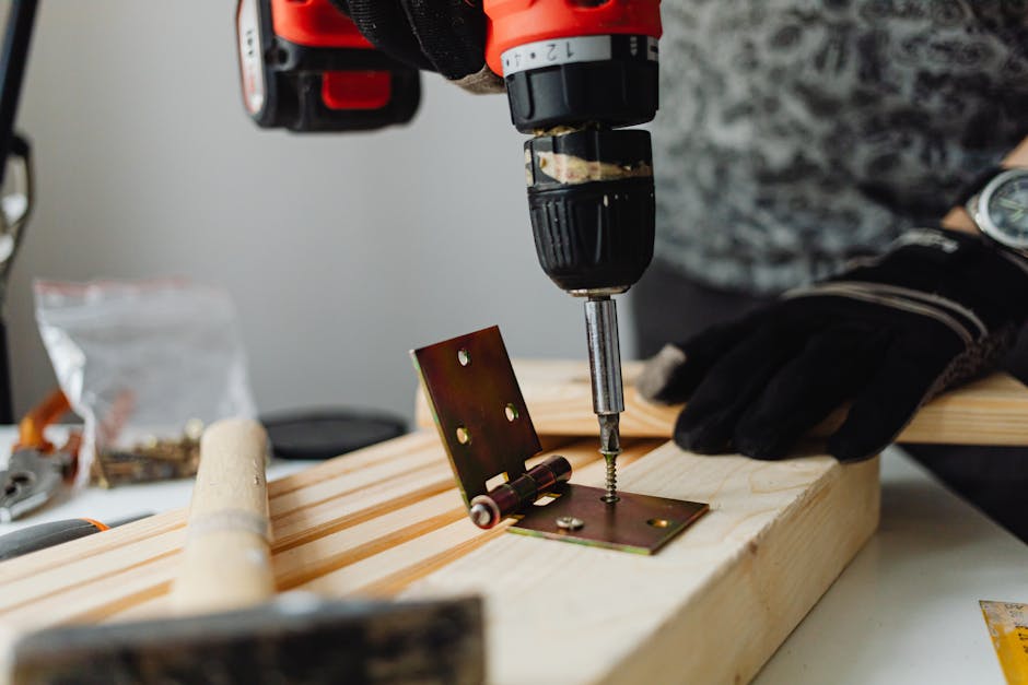 Close-up of a skilled carpenter using a power drill on wood in a workshop.