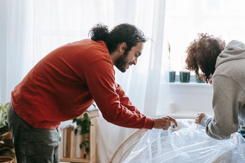 A couple wrapping furniture with bubble wrap while moving into a new home.