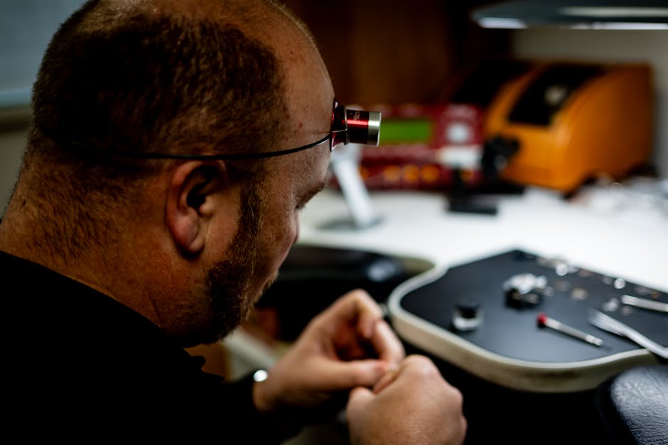 Watchmaker focused on repairing a watch with precision tools at a workbench.
